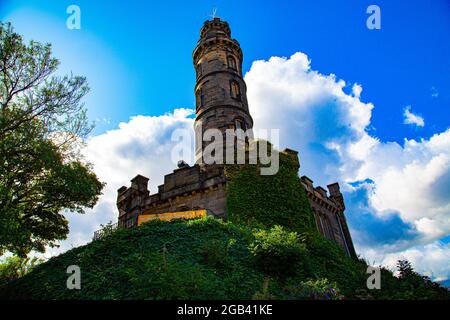 Stone bell tower with ornate stone wall base and surrounded by vegetation, on a small hill Stock Photo