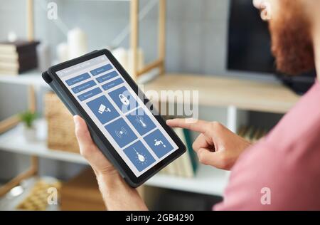 Man using an app on a modern tablet computer to control the system of his Smart House Stock Photo