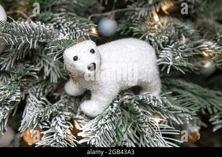 Photo of white teddy bear sitting on Christmas tree in snow, Christmas tree decor, festive concept, lights Stock Photo