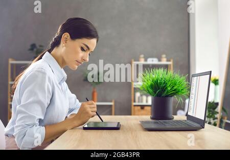 Elegant young business woman working with modern digital tablet and laptop in her office. Stock Photo