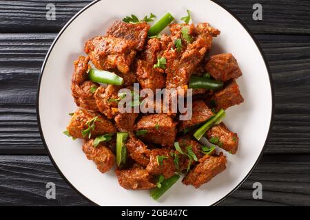 Tibs is an Ethiopian dish consisting of stir-fried meat and vegetables closeup in the plate on the table. Horizontal top view from above Stock Photo