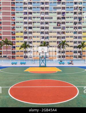 HONG KONG - 10TH APRIL 2017: A basketball court and colourful facades and architecture in Kowloon, Hong Kong. People can be seen. Stock Photo