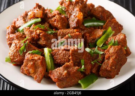 Tibs is an Ethiopian dish consisting of stir-fried meat and vegetables closeup in the plate on the table. Horizontal Stock Photo