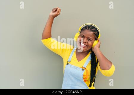 Happy African American woman using a smartphone and enjoying music with headphones while on the street. Stock Photo