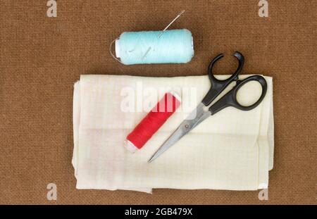 Group of sewing tools and items for knitting and weaving placed on a brown colour woven paper board. DIY Art and craft background concept. Stock Photo
