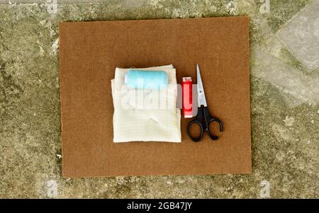 Group of sewing tools and items for knitting and weaving placed on a brown colour woven paper board. DIY Art and craft background concept. Stock Photo