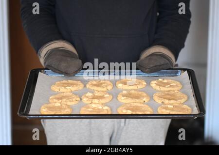 Photo of a man holding a plate full of round freshly baked cookies Stock Photo