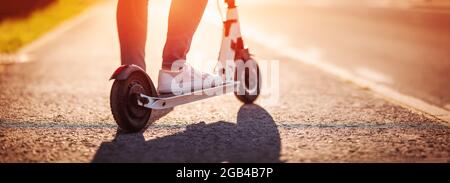 Woman riding on scooter on asphalt in summer Stock Photo