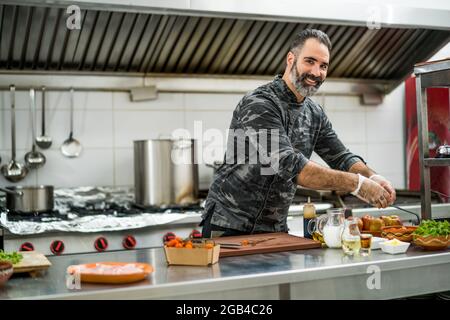 Professional cook is ready for preparing meal in restaurant's kitchen. Stock Photo