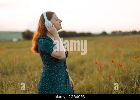 Close up portrait of stylish young girl meditates with white wireless headphones outdoors Stock Photo