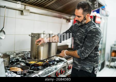 Professional cook is preparing meal in restaurant's kitchen. Stock Photo