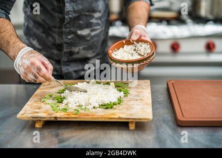 Professional cook is serving meal in restaurant's kitchen. Stock Photo