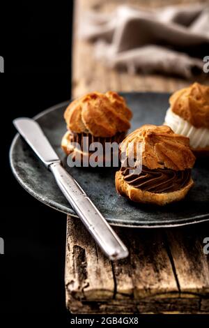 Chocolate and cream profiteroles on rustic wooden table Stock Photo