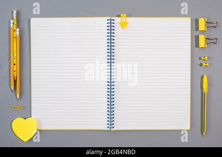 Assorted yellow office and school stationery supplies with open blank block note on gray background, top view, copy space Stock Photo