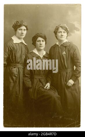 Original, sharp and clear image of WW1 era postcard of a group of attractive women munitions workers, wearing Ministry of Munitions  'on war service' triangular badges indicating the girls were on war service. From the studio of Boughtons, Ipswich, U.K circa 1916-1918. Stock Photo