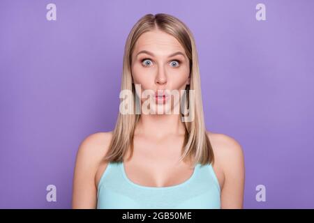 Photo of impressed blond young lady wear teal top isolated on violet color background Stock Photo