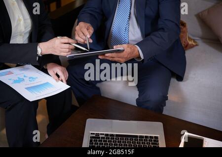Close-up image of business partners pointing at tablet computer when discussing new strategy of company developent and past accomplishment Stock Photo