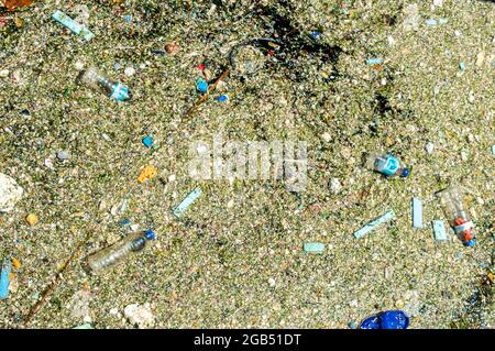 dirty layer and plastic litter that has covered the sea surface. Plastic bottles float on the surface of the water.