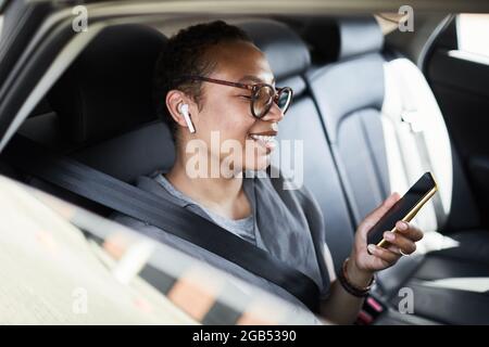 African businesswoman smiling and talking on video using her mobile phone during her trip in the car Stock Photo