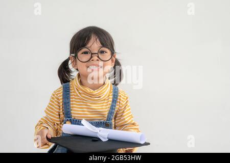 children girl wearing a graduate cap over white background very happy and excited doing winner gesture with arms raised, smiling and screaming for suc Stock Photo