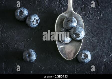 Fresh sweet blueberry berries in the silver spoon on black background. Food photography Stock Photo