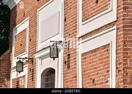 The lamp, stylized as an old one, hangs on a brick wall of a historic building. Summer. Stock Photo