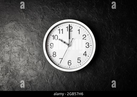 Wall clock on the black texture background. Flowing time concept Stock Photo