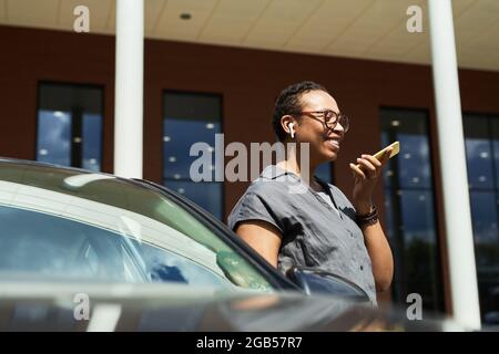 Happy woman standing near the car in the city and talking on mobile phone Stock Photo