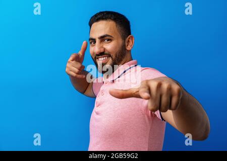 Young arab man pointing to you and the camera with fingers against blue background Stock Photo