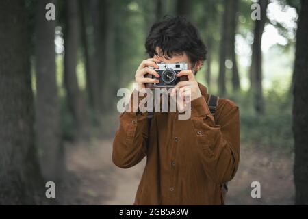 Photographer in brown jacket with retro camera in summer park Stock Photo