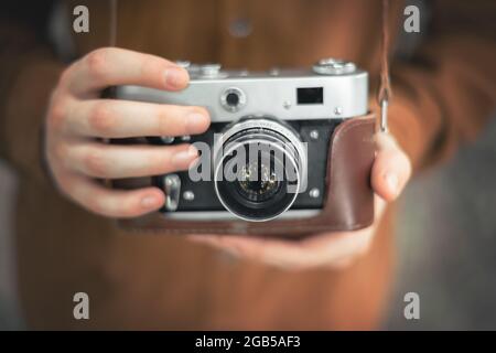 Photographer in brown jacket taking in hands retro camera closeup Stock Photo