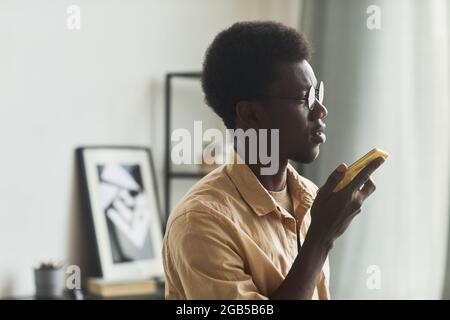 Close-up of African young man using his mobile phone for online conversation at office Stock Photo
