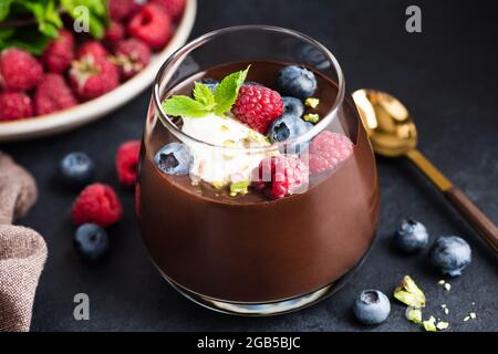 Thick Chocolate Mousse With Cream Berries And Pistachios In Glass On Black Stone Background. Luxury Dessert Dark Chocolate Mousse Stock Photo