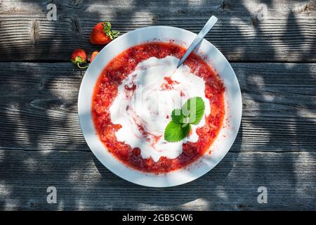 Soup from fresh strawberry berries, sugar and sour cream with mint leaf on wooden table Stock Photo