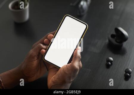 Close-up of man holding mobile phone with empty touch screen in his hands and using new application at the table Stock Photo