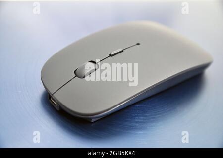 Wireless rechargeable computer mouse on a blue background. Technology Stock Photo