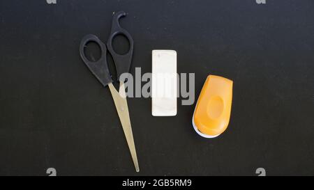 Scissors, Eraser, and a Stapler on a Black Background Stock Photo