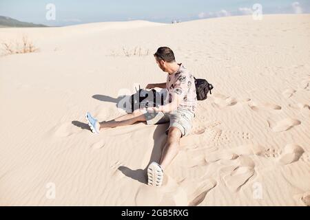 The drone pilot prepares to take off the aircraft from hand on a fine sand dune Stock Photo