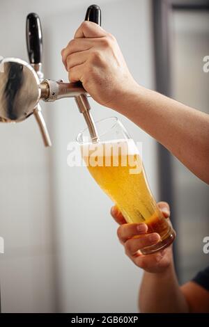 Hands pouring draught beer into a glass Stock Photo