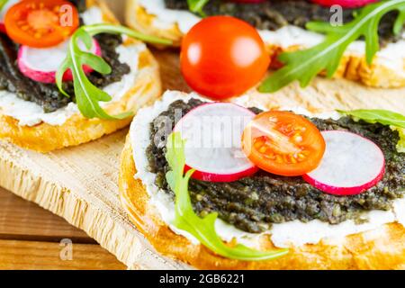 Vegan sandwiches with avocado cream. Healthy sandwiches with cream cheese, avocado, radish and cherry tomatoes. Close-up Stock Photo
