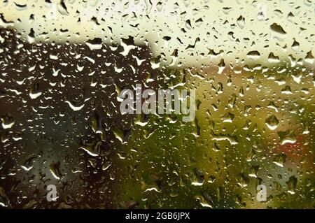 Drops on the glass on a rainy day, blurred silhouette of the house in the background. Autumn. Stock Photo