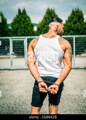 Strong young man tearing handcuffs in park Stock Photo