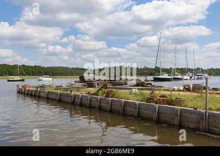 Buckler's Hard, Hampshire, UK, June 23rd 2021: A rusty anchor and chains on a wooden quayside juts into the Beaulieu River on which yachts are moored. Stock Photo