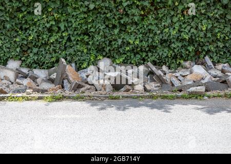 paving work to renew the walkway, destroyed old stones, hedge in the background Stock Photo