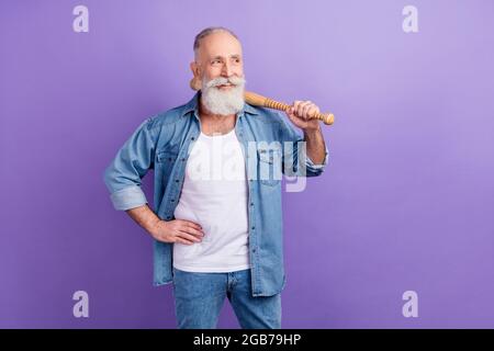 Photo of confident cute age gentleman wear jeans shirt arm waist holding bit looking empty space isolated violet color background Stock Photo