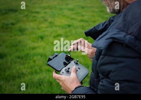 Middle aged man in outdoors clothing operating a Drone in the countryside. Stock Photo