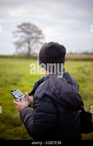Middle aged man in outdoors clothing operating a Drone in the countryside. Stock Photo