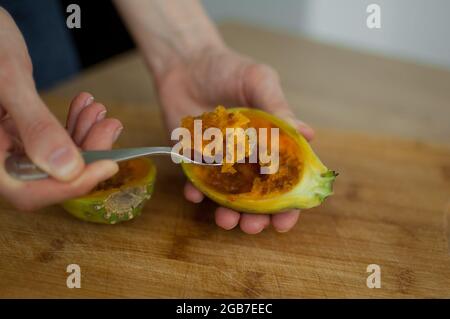 Female eats fresh organic ripe cactus pear or opuntia with a spoon. Exotic fruits, healthy eating concept Stock Photo