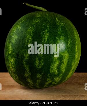 Whole watermelon on wood board on black background Stock Photo
