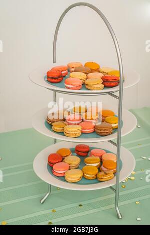 Three tiers of plates full of colorful French Macaron pastries for dessert Stock Photo